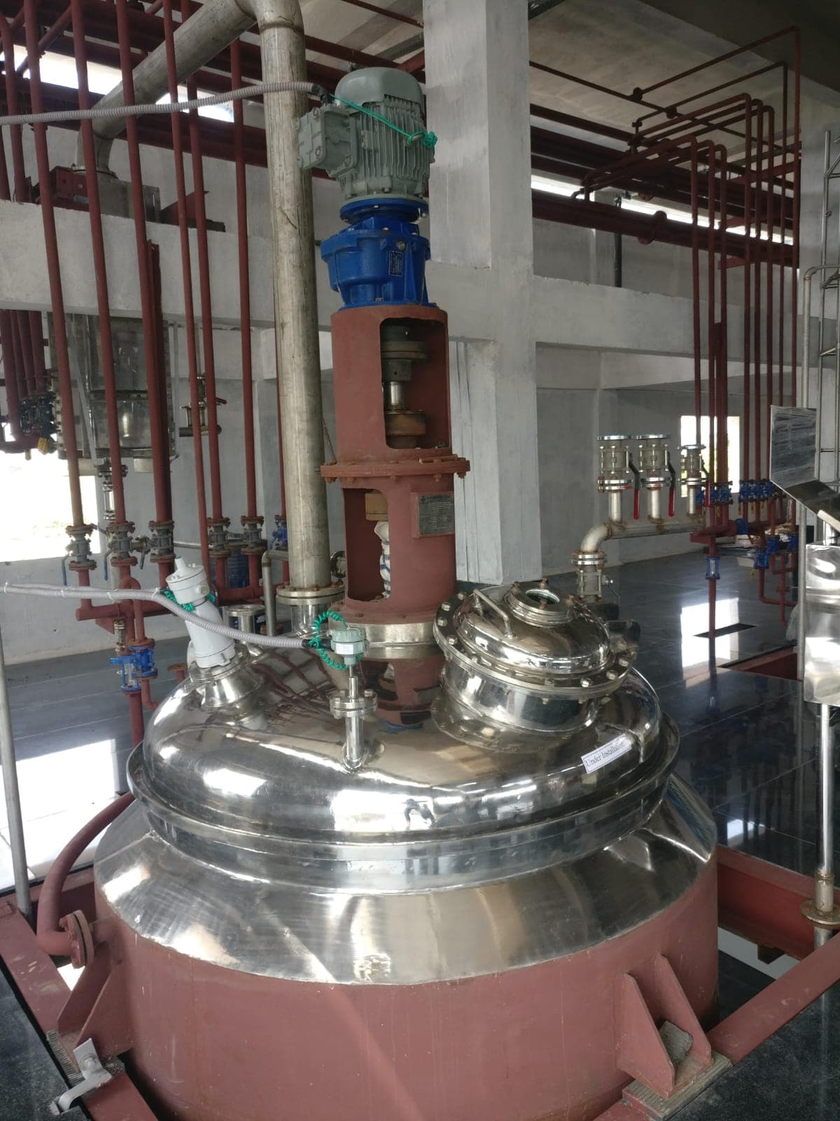 Stainless steel reactor with agitator motor in production hall